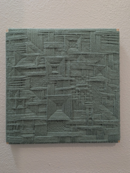 A green abstract weaving with repeating square motifs and layered strands