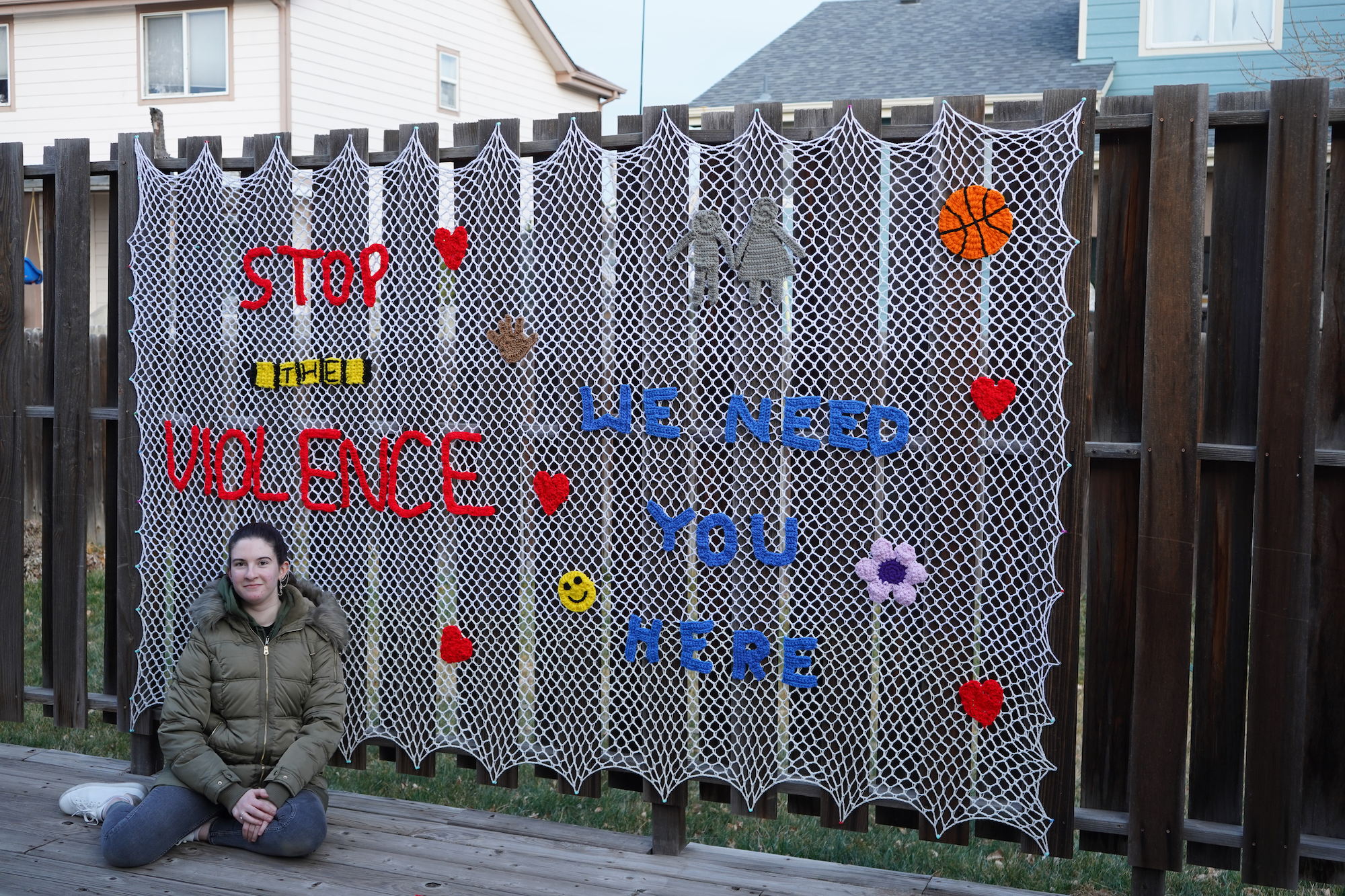 Joey sitting beside her Stop the Violence yarn-bombing senior project